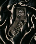 Black grip sock with textured sole on a dark fabric background