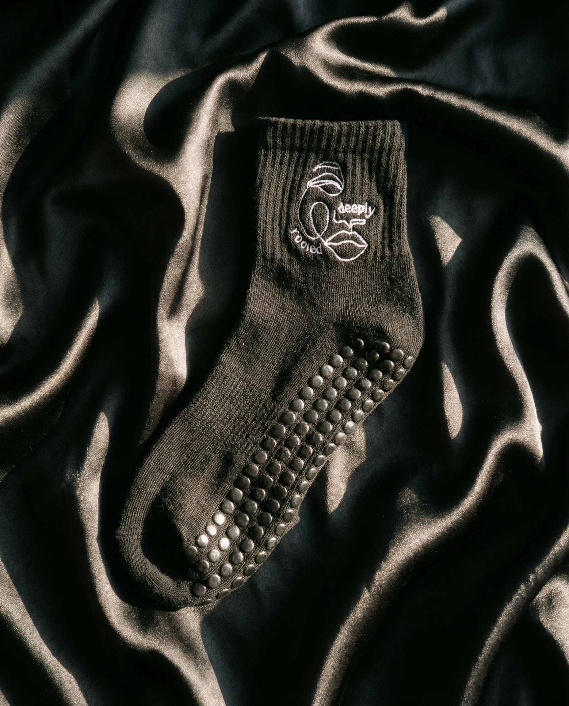 Black grip sock with textured sole on a dark fabric background