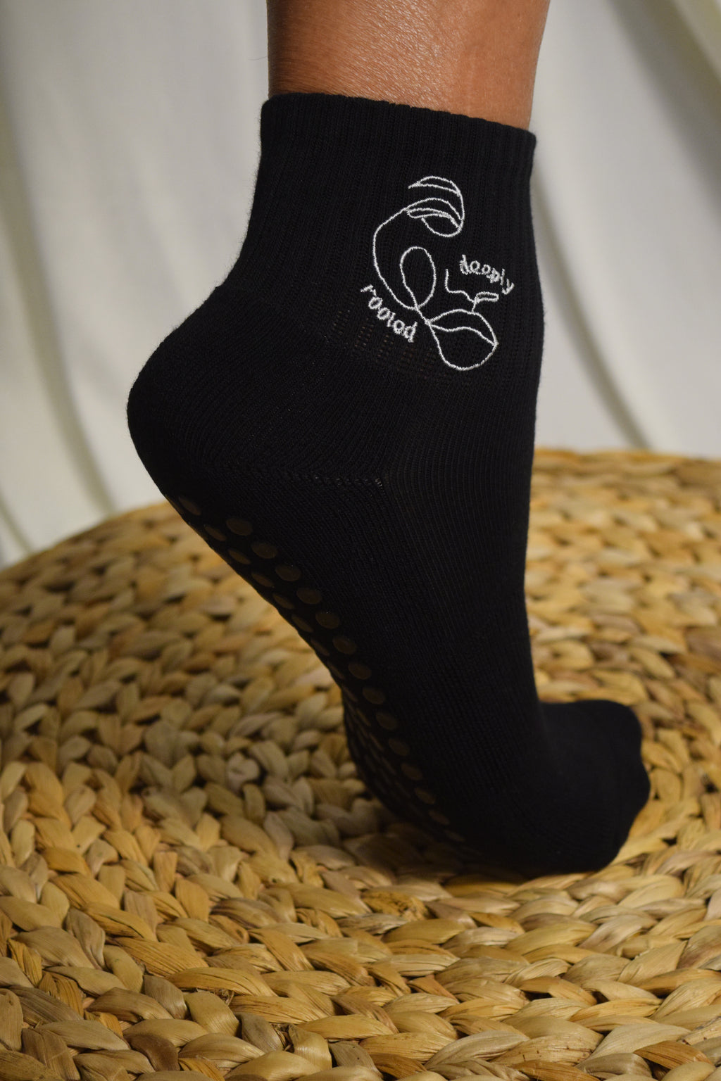 Model's foot wearing Deeply Rooted Grip Sock Set on top of a raffia pouf