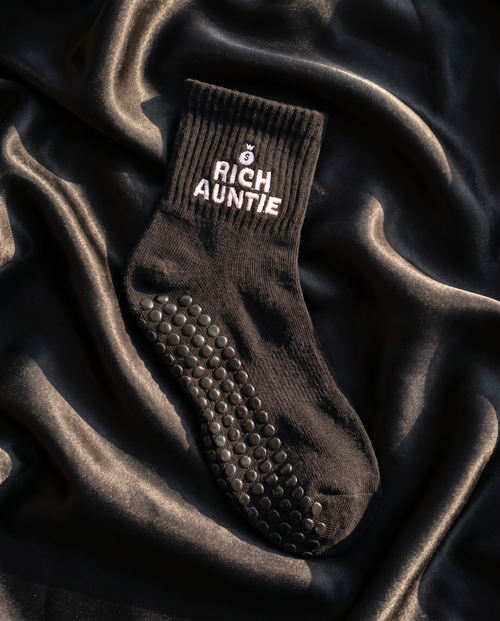 Black grip sock with 'Rich Auntie' text on a dark fabric background