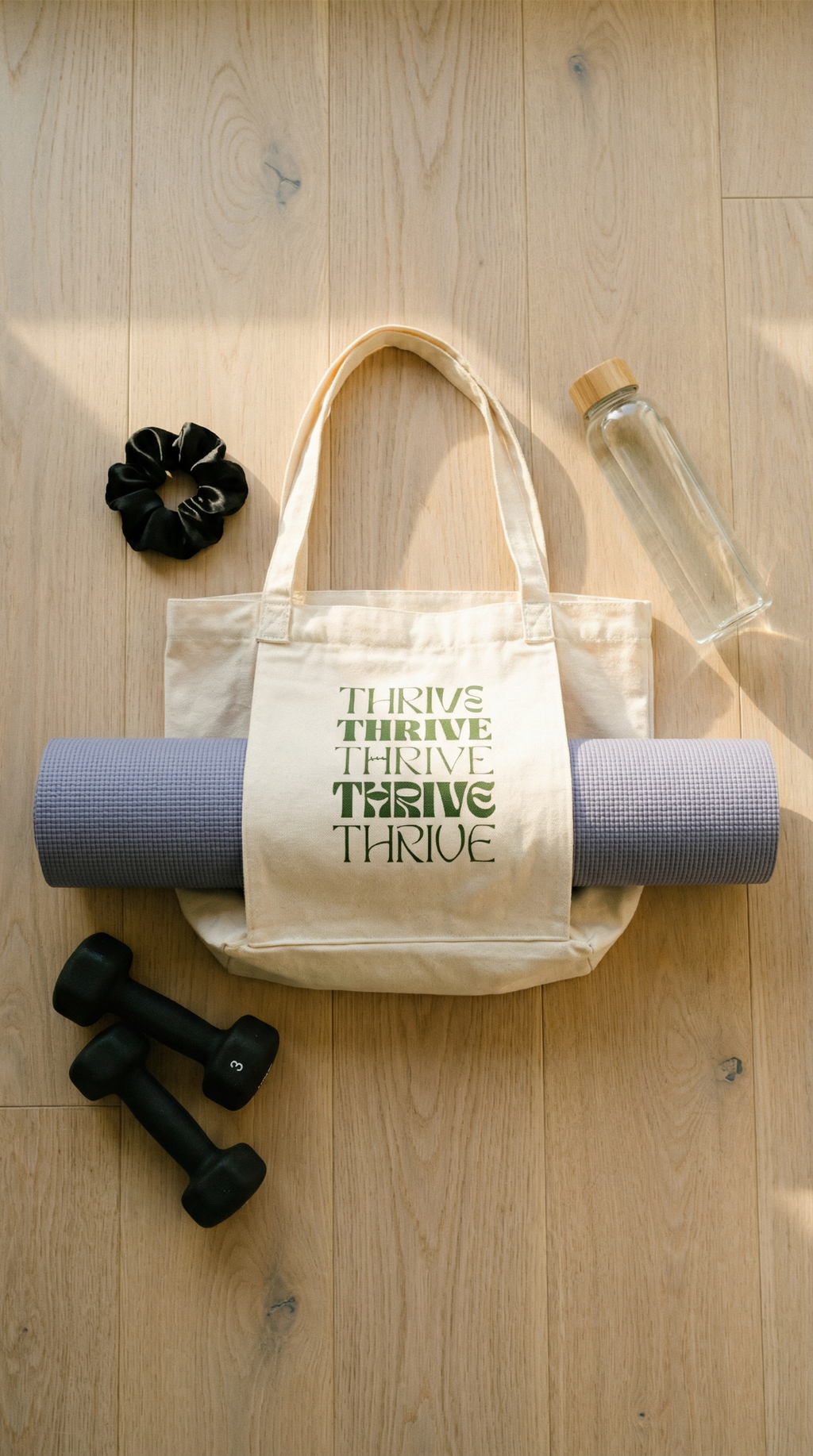 Tote bag with 'Thrive' text, yoga mat, water bottle, and dumbbells on a wooden floor.